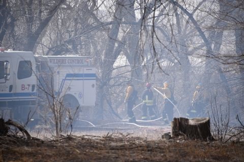 Two fire fighters and an engine on scene of a wildfire