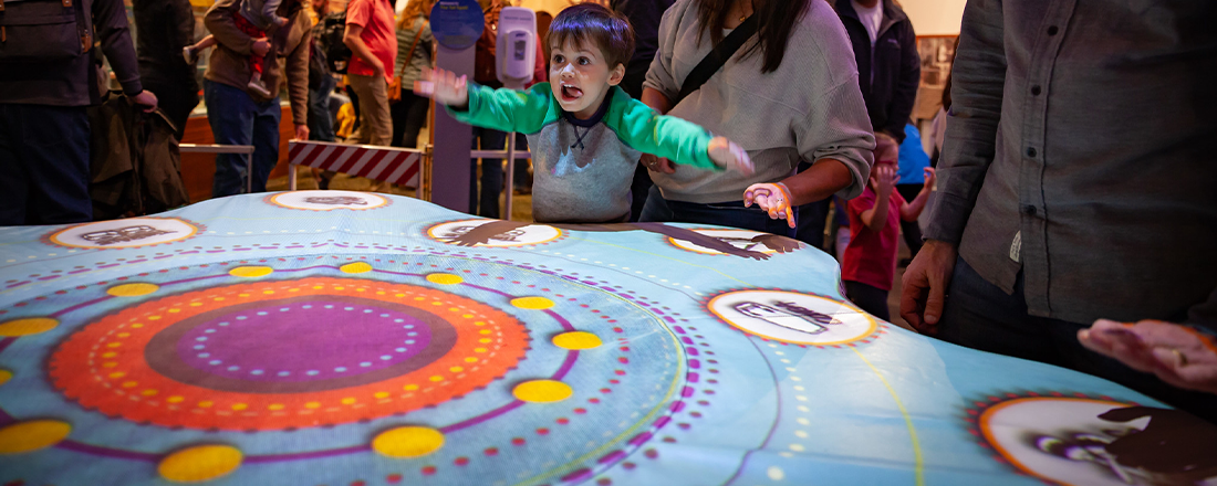 child gestures wildly at interactive table