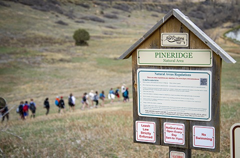 Pineridge Natural Area sign in the shale of a small wood house telling visitors the rules of the natural area.