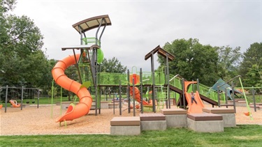 A playground at a park surrounded by trees