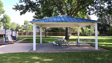 A park pavilion shaded by trees with a picnic table