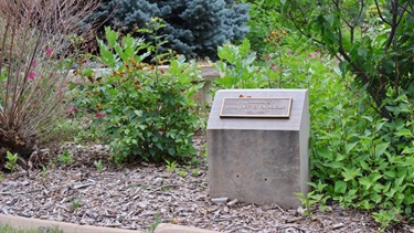 A stone placard in front of a pollinator garden