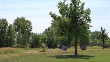 Two sculptures resembling orange slices in a park