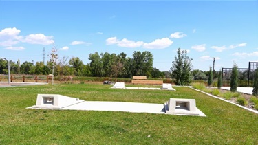 Two sets of concrete cornhole boards on green grass