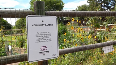 A sign for a community garden in a park