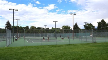 People playing on tennis courts at a park