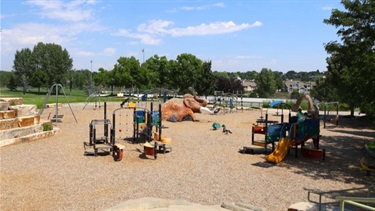 A playground with various play structures, a wooly mammoth sculpture and slides