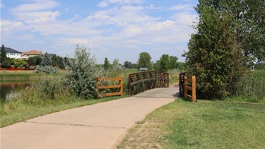 A paved trail with a bridge over a creek