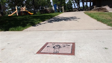 A square piece of tile art on a sidewalk at Harmony Park
