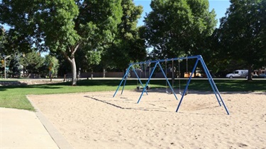 A swing set in a sand-filled playground