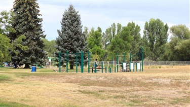 A fitness course structure in a field of golden grass surrounded by trees