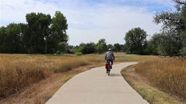 A man rides a bicycle down a paved trail