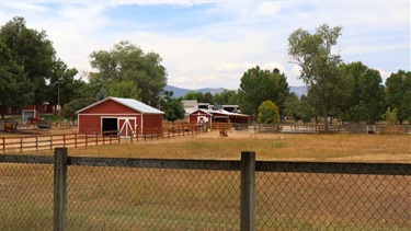 A red barn behind a fence and a field