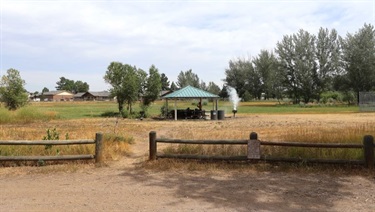 A small covered pavilion in a wide open park
