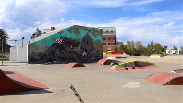 A skate park featuring a large mural on the side of a building