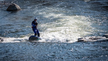 A person surfing in the Poudre River rapids
