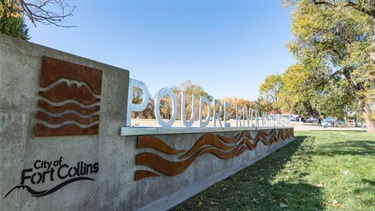 A stone structure with the City of Fort Collins logo and the words Poudre River Whitewater Park