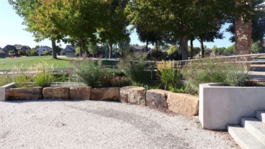 Art representing water engraved in gravel in front of a flowerbed