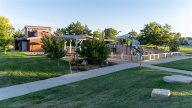 A sidewalk running past a park on a sunny day