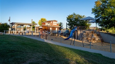 A park playground with a slide and boulder climbing features