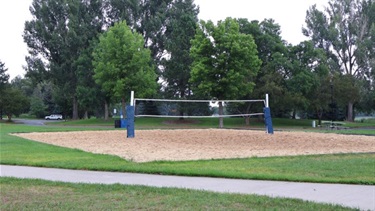 A sand volleyball court surrounded by trees and green space