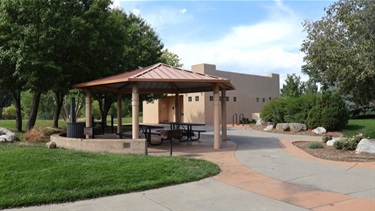 A covered shelter next to paved trails in a park