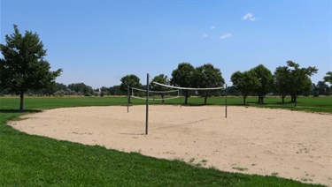 Two sand volleyball courts surrounded by green space