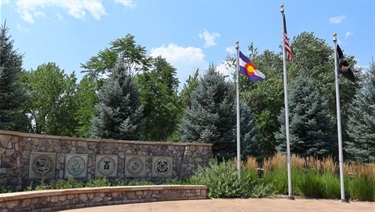 Three flags and a rock structure at a Veterans Memorial display