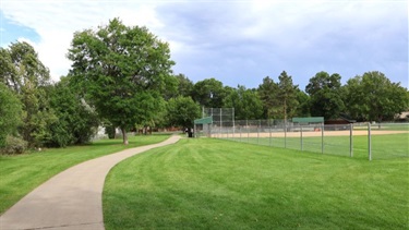 A paved path running past ballfields at a park