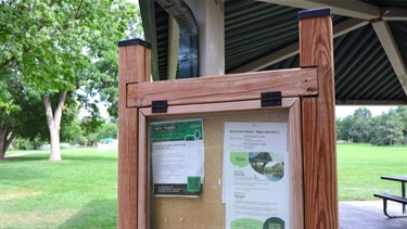 A wooden sign outside a park pavilion with reservation information