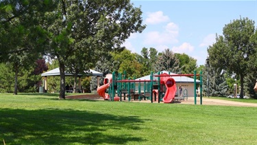 A playground in a park surrounded by trees