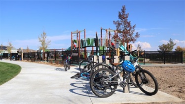 Bikes lean against bike racks next to a park playground
