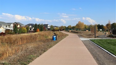 A paved path running by a park near a neighborhood