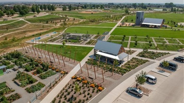 An aerial shot of a park with a playground, shelter, green space and gardens