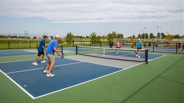 People play pickleball on a blue and green court