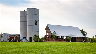 A park playground with a covered shelter and two grain silos