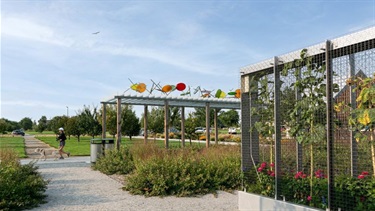 A sidewalk next to a wall of flowers and a pavilion
