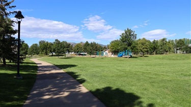 A path running through a park with a playground and open green space