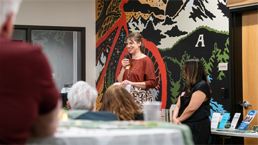 person talks into microphone to groups at tables