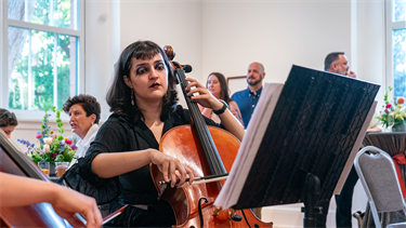 person plays cello in bright indoor venue