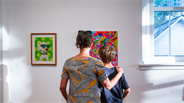 parents and child stand in front or artwork in gallery