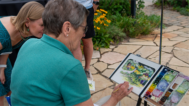 person paints outdoors on garden path